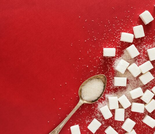 당분 섭취 줄이기가 체중 감량에 미치는 영향 sugar cubes and a spoon on a red surface